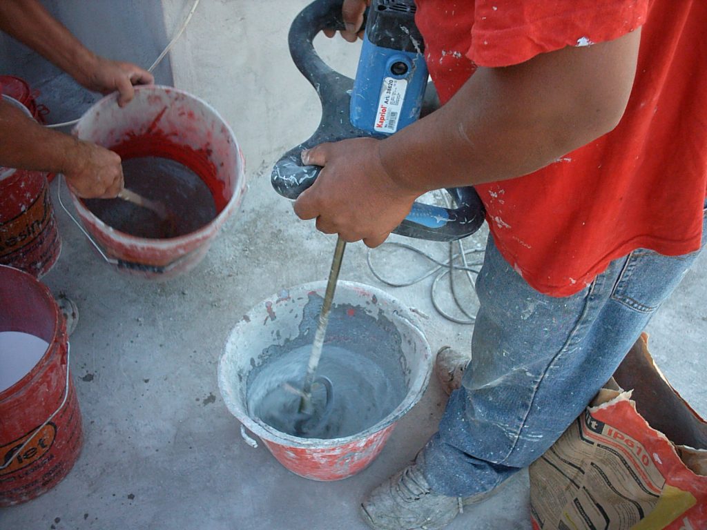 operaio impasta cemento con trapano miscelatore